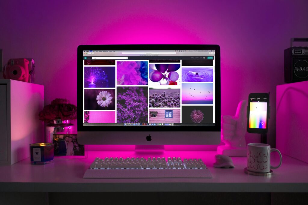 pexels-photo-1779487-1779487 Modern desk setup with neon lighting and a desktop computer displaying colorful images.